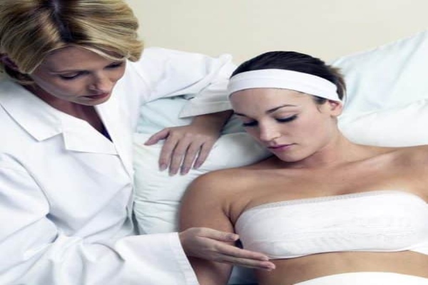 Doctora evaluando a una paciente luego de realizar la cirugía de aumento de pechos, para verificar que todo marcha correctamente