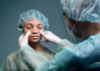 Clínicas de rinoplastia en España - Doctor comenzando a tratar la zona de la nariz de una paciente femenina, para realizar la cirugía de rinoplastia y mejorar su estética