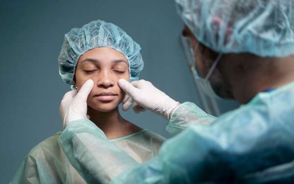 Clínicas de rinoplastia en España - Doctor comenzando a tratar la zona de la nariz de una paciente femenina, para realizar la cirugía de rinoplastia y mejorar su estética