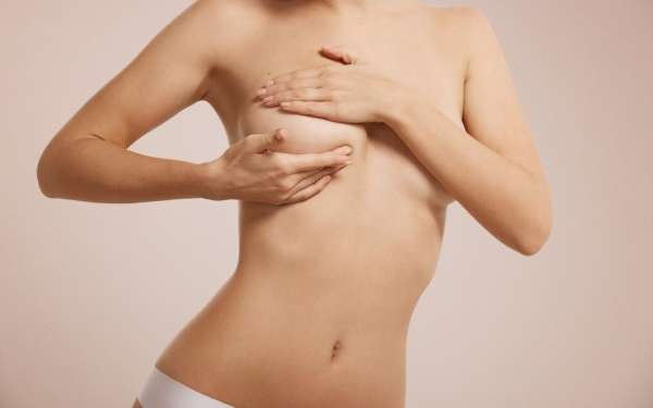 clínicas de levantamiento de pecho en Las Palmas - Mujer con el torso desnudo comprobando con sus manos cuales podrían ser los resultados de un levantamiento de pecho
