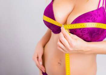 Mujer en ropa interior usa una cinta métrica para medir el tamaño de sus senos previo a una cirugía