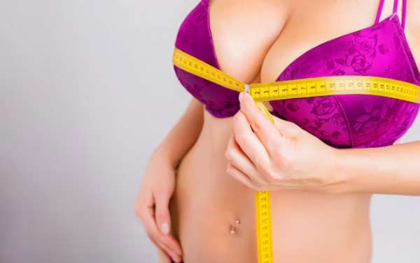 Mujer en ropa interior usa una cinta métrica para medir el tamaño de sus senos previo a una cirugía