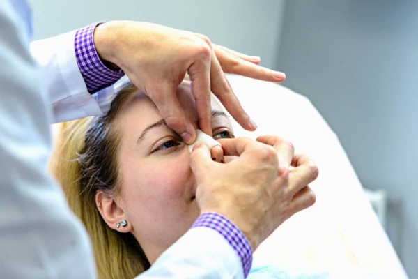 clínicas de rinoplastia en Las Palmas - Mujer operada de rinoplastia en la consulta del cirujano plástico realizando una revisión postoperatoria