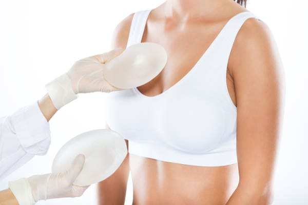 Las mejores clínicas de aumento de pecho en Bilbao - mujer en la consulta del cirujano plástico el cual le muestra varios implantes mamarios para realizar un aumento de pecho