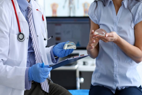 clínicas de aumento de pecho en Bilbao - mujer en la consulta del cirujano plástico revisando con el especialista varios implantes de mamas para elegir el que va implantarse