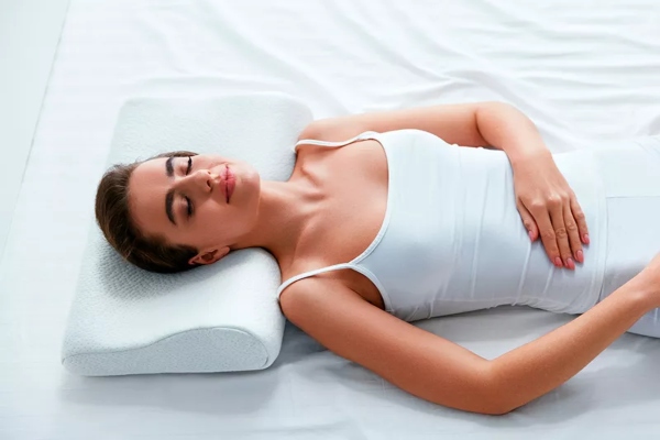 clínicas de abdominoplastia en Bilbao - mujer tumbada en la cama con una almohada ergonómica, durmiendo feliz con los resultados de la abdominoplastia