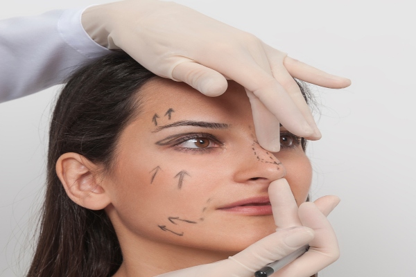 Las mejores clínicas de rinoplastia en Las Palmas - mujer en la consulta del cirujano plástico recibiendo las explicaciones de como va a realizarse la rinoplastia mientras el cirujano dibuja las líneas de la cirugía