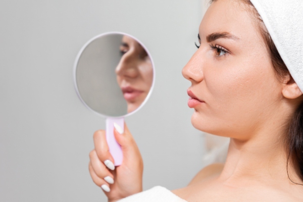 clínicas de rinoplastia en Las Palmas - imagen de una mujer revisando los efectos de la rinoplastia, reflejándose en el espejo como era antes la nariz