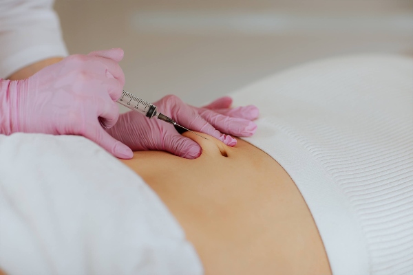 Las mejores clínicas de carboxiterapia en Barcelona - Dermatóloga aplica una serie de microinyecciones en el abdomen de una paciente para disolver la grasa localizada y potenciar la firmeza de la piel