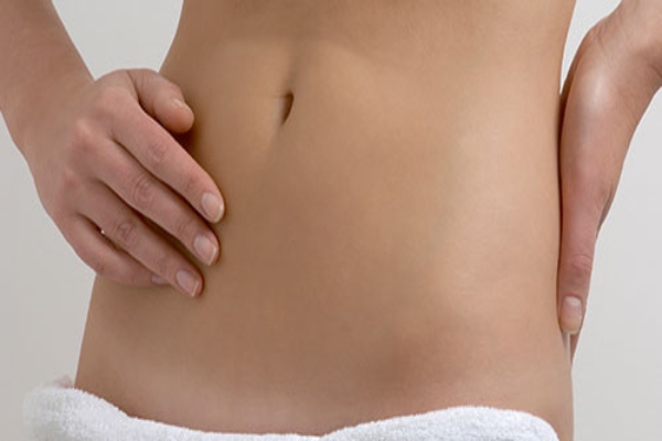 Joven con abdomen descubierto disfruta de los beneficios de un tratamiento estético para deshacerse de la grasa localizada
