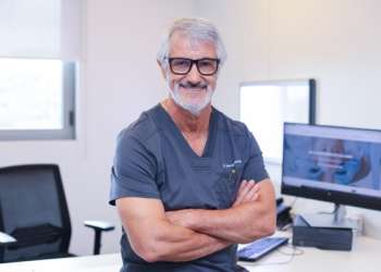 Doctor en rinoplastia en Barcelona - Perfil del Dr. Barceló Colomer con lentes y ropa de trabajo desde su consultorio