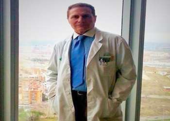 doctor de liposucción en Madrid - el Dr. Lajo Rivera con ropa de consulta de pie al lado de un ventanal