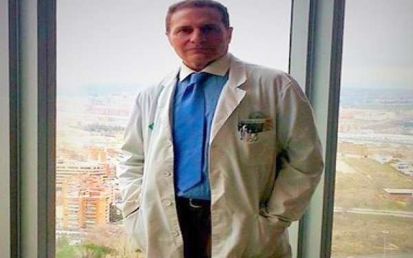 doctor de liposucción en Madrid - el Dr. Lajo Rivera con ropa de consulta de pie al lado de un ventanal