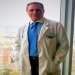 doctor de liposucción en Madrid - el Dr. Lajo Rivera con ropa de consulta de pie al lado de un ventanal