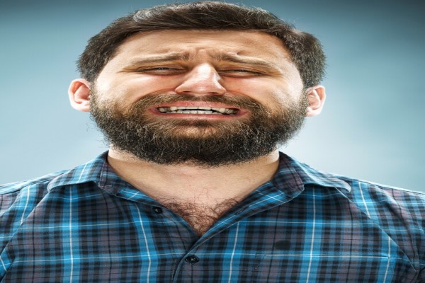 Hombre con camisa de cuadros hace gesto de frustración e inconformidad en relación a la apariencia achatada y poco estética de su nariz