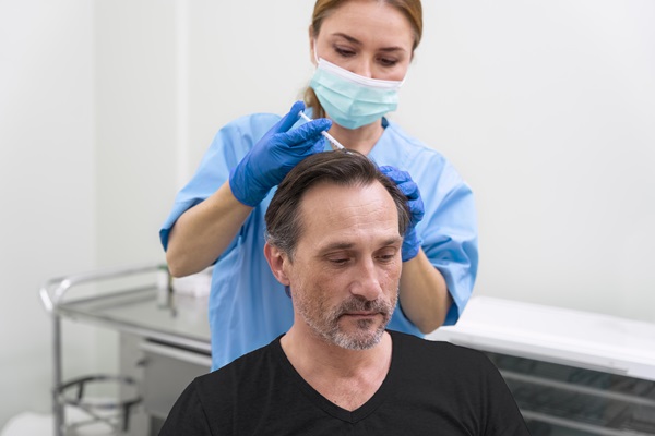 Doctora realizando un trasplante de cabello a un paciente masculino