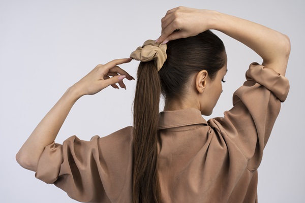 Mujer amarrando su cabello con un moño, lo cual aumenta la sensibilidad del cuero cabelludo