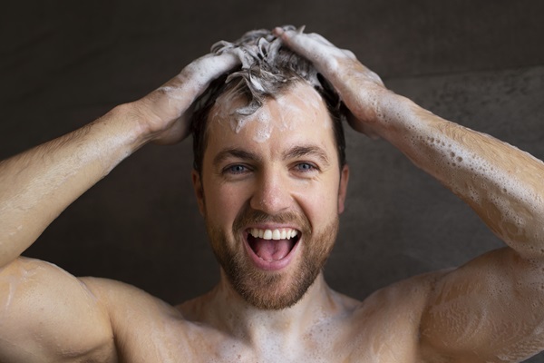 Lavarse el pelo todos los días - Hombre feliz al lavar su cabello con un champú natural, que protege su pelo al no tener químicos