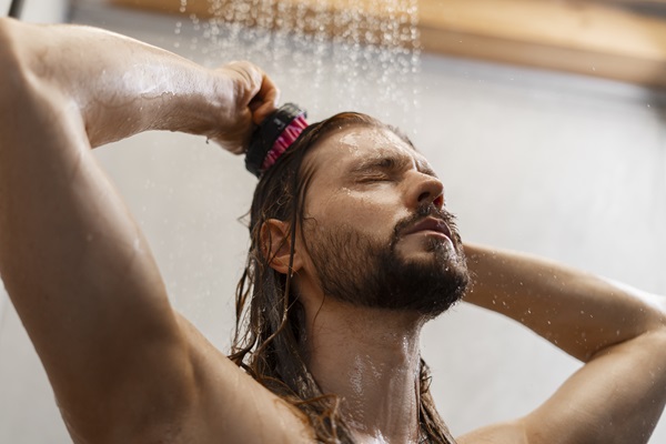 Hombre lavando su cabello con un masajeador, utilizando agua tibia para controlar la producción de sebo