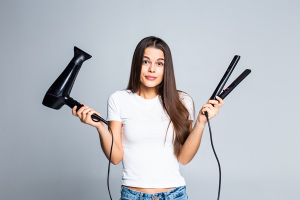 Mujer confusa por no saber si escoger la plancha o el secador para alisar su cabello