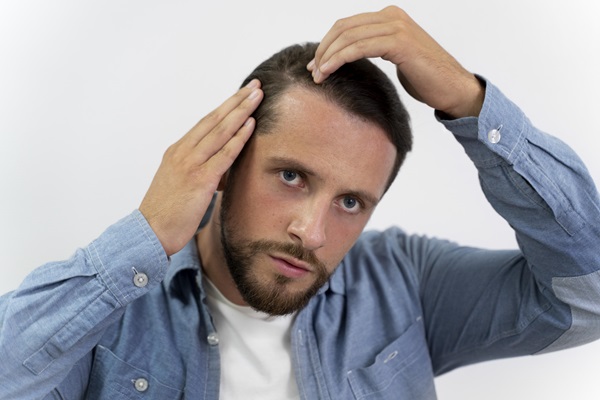 Hombre peinándose con delicadeza, para cuidar su cabellera luego del implante de pelo