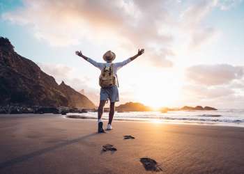 Cirujanos capilares en Las Palmas de Gran Canaria - Hombre feliz en una playa de Las Palmas, haciendo turismo mientras visita Gran Canaria por un tratamiento de implante de cabello