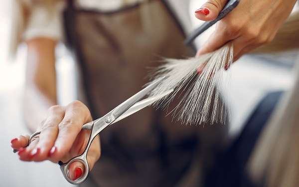 Cuántos pelos tenemos en la cabeza - Estilista cortando las puntas abiertas de un cabello con tratamiento químico
