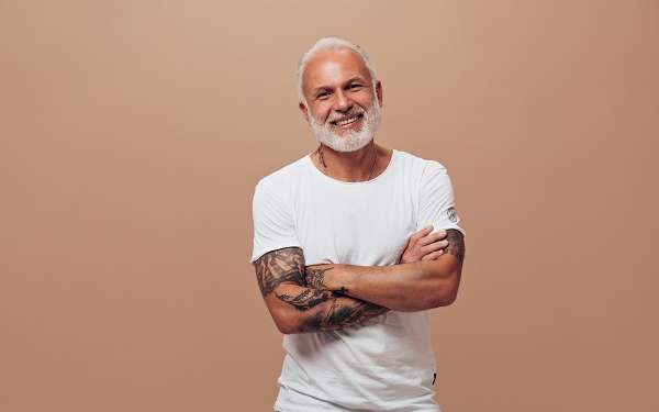¿Cómo envejece nuestro pelo? - Hombre adulto con el pelo y la barba llenas de canas con los brazos cruzados sobre el pecho