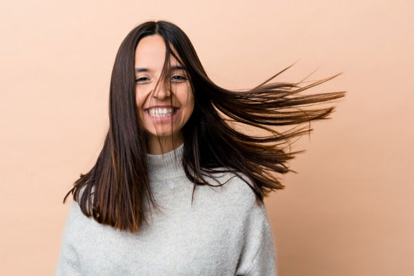 Kit para el cuidado del cabello - Chica de pelo graso en movimiento sonríe ante la cámara