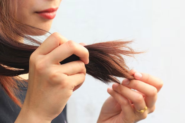 Kit para el cuidado del cabello - Mujer de labios rojos se detiene a apreciar las puntas abiertas de su melena