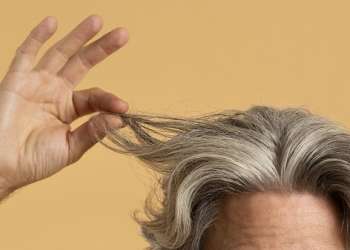 ¿Cómo lucir las canas con estilo? - hombre adulto sujetando un mechón de su cabello con canas