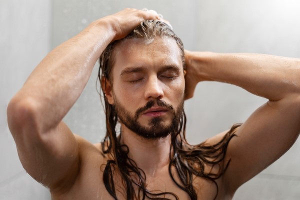 cuidar el pelo en los hombres - hombre en la ducha aclarándose el champú del cabello