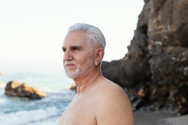 envejece nuestro pelo - hombre mayor con el pelo lleno de canas en la playa