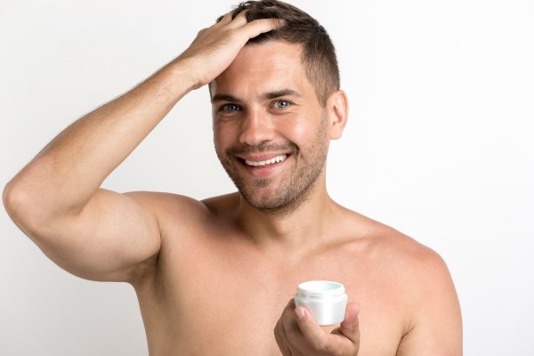 hombre aplicando cera para el cabello en su melena