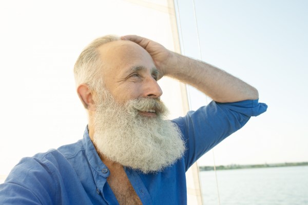 envejece nuestro pelo - hombre mayor con el pelo y la barba llena de canas con claros signos de alopecia en las entradas y la frente en un barco