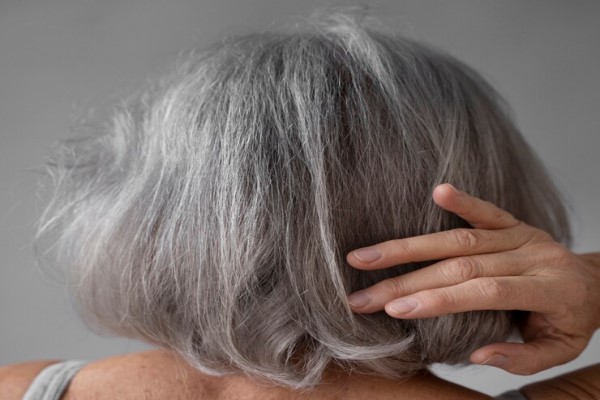 envejece nuestro pelo - mujer mayor de espaldas con el cabello seco y con canas