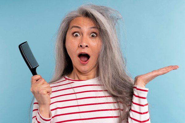 mujer mayor sorprendida por el encrespamiento de su melena canosa por el envejecimiento del cabello