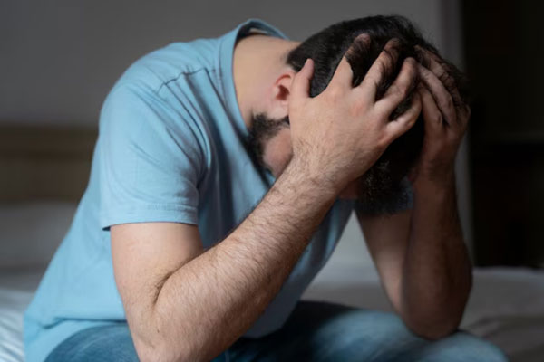 Salud mental en el hombre - Hombre preocupado con las manos en la cabeza a orillas de la cama