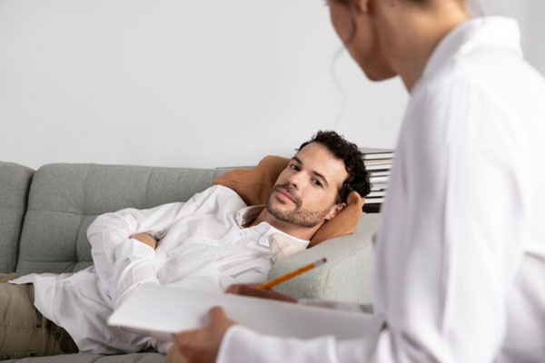 Salud mental en el hombre - Psicóloga toma nota de los síntomas de un paciente masculino con problemas de ansiedad
