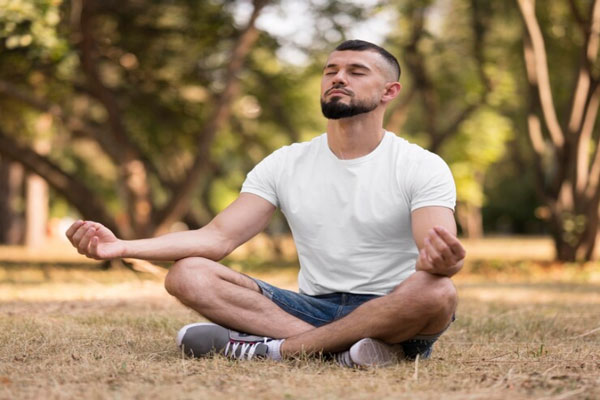 Hombre medita y realiza ejercicios de respiración al aire libre