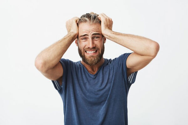 Salud mental en el hombre - Joven deprimido y emocionalmente afectado tira de su cabello con las manos