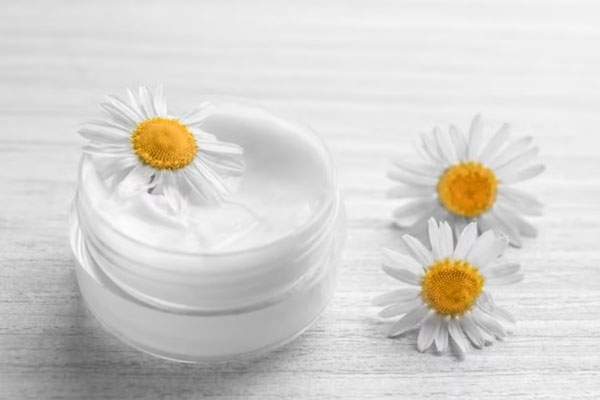 Insumos para preparar una mascarilla de yogur y de aceite de manzanilla sobre una superficie de madera