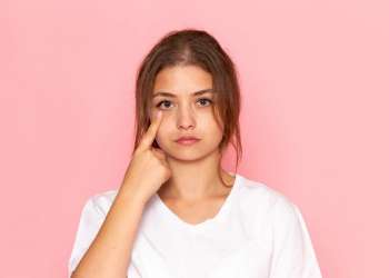 bolsas en los ojos - Joven de mirada cansada señala la parte baja de su párpado