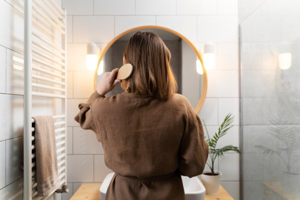 joven cepillándose la melena tras secarla siguiendo las indicaciones de como cuidarse el cabello
