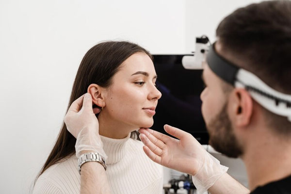 Cirujano examina los rasgos faciales de una mujer para realizarle una otoplastia