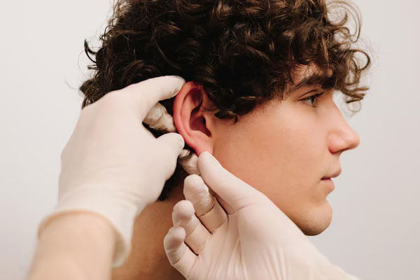 Cirujano plástico evalúa el lóbulo de la oreja de un paciente antes de realizar una otoplastia