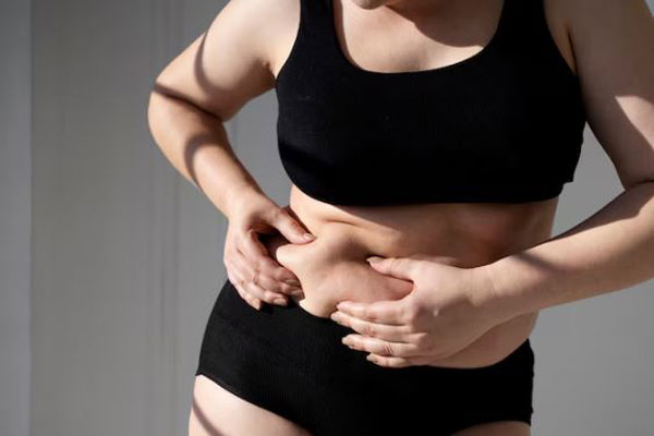 Flacidez abdominal - Mujer con exceso de grasa localizada en ropa interior aprieta la piel de su abdomen