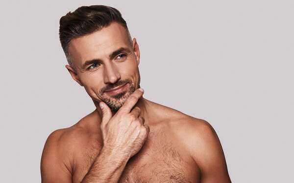 Belleza masculina - Caballero tocando su rostro rejuvenecido luego de aplicarse el mejor tratamiento facial hombre en Madrid