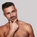 Belleza masculina - Caballero tocando su rostro rejuvenecido luego de aplicarse el mejor tratamiento facial hombre en Madrid