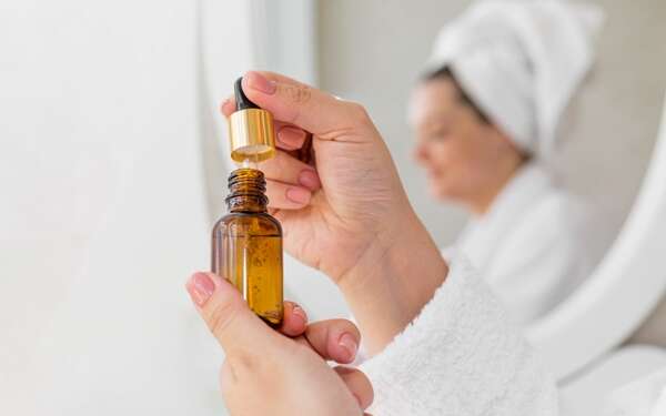 Aceites esenciales para el cuerpo - Mujer utilizando los aceites esenciales naturales más usados en España para hidratar la piel